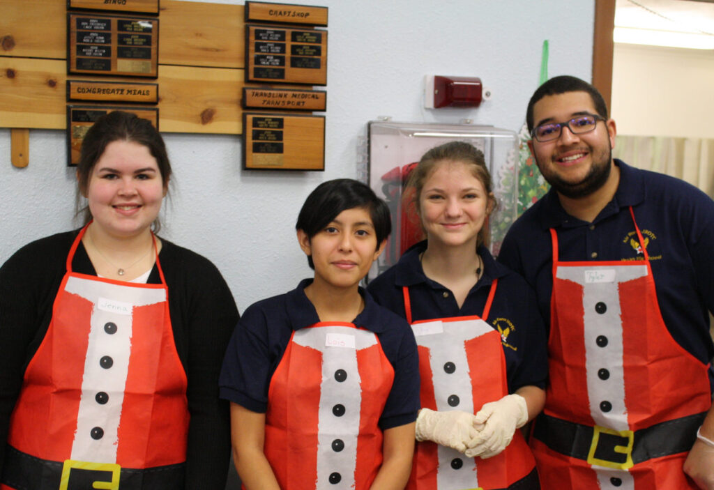 A group of younger volunteers wearing Santa aprons.